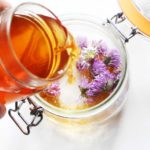 vinaigre de cidre versé sur des fleurs de ciboulette dans un bocal